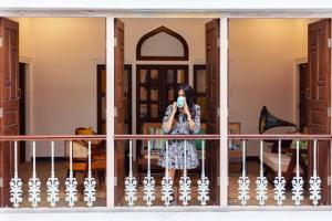 una mujer de pie en un balcón tomando una foto en Kanak Vilas by StayVista, a Rajasthani haveli boutique stay with hill views, offering both indoor and outdoor games for a delightful retreat, en Jaipur