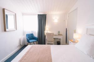 een slaapkamer met een bed en een blauwe stoel en een bureau bij Fleur de Sel in Noirmoutier-en-l'lle