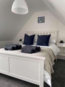 a white bed with blue pillows on top of it at Tidal Walk Cottage by the Sea in Harwich