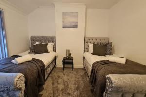 a bedroom with two beds and a table in it at Saint Johns 3-bedroom House-Greater London in Dartford