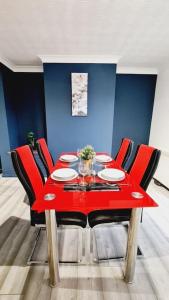a red dining table with red chairs in a room at Saint Johns 3-bedroom House-Greater London in Dartford