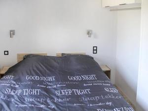 a bed with a black comforter with the words good night on it at Holiday Home Natuurlijk de Veenhoop by Interhome in De Veenhoop