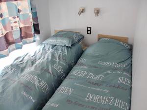 a bedroom with two beds with green comforters and words on them at Holiday Home Natuurlijk de Veenhoop by Interhome in De Veenhoop