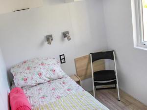 a small bedroom with a bed and a chair at Holiday Home Natuurlijk de Veenhoop by Interhome in De Veenhoop