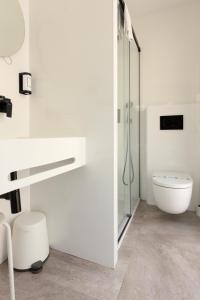 a white bathroom with a shower and a toilet at Hotel La Milagrosa in Alicante