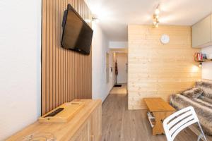 ein Wohnzimmer mit einem Sofa und einem Fernseher an der Wand in der Unterkunft SweetLoc - Appt au pied des Pistes au Corbier in Villarembert