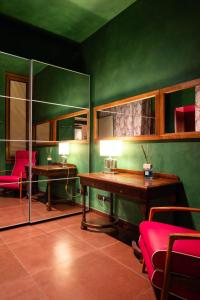 Grünes Zimmer mit einem Schreibtisch, einem Tisch und Stühlen in der Unterkunft Hotel Caravaggio in Florenz