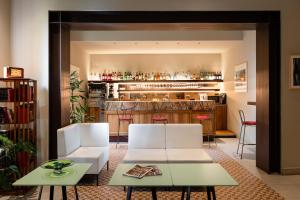 a living room with two white chairs and a bar at Hotel Caravaggio in Florence