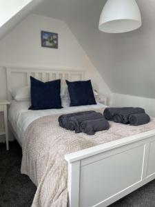 a white bed with two black towels on it at Tidal Walk Cottage by the Sea in Harwich
