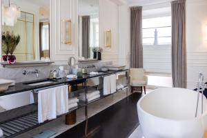 bagno con vasca e grande specchio di Hotel Vilòn - Small Luxury Hotels of the World a Roma