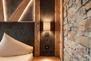 um quarto com uma cama com um candeeiro e uma parede de pedra em Hotel Kohlerhof em Fügen