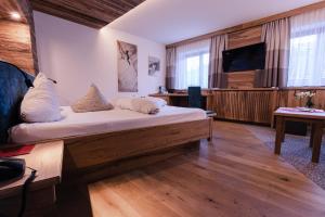 a bedroom with a large bed and a flat screen tv at Hotel Kohlerhof in Fügen