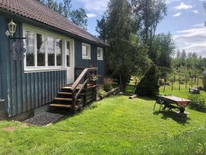ein kleines Haus mit einer Holztreppe neben einem Hof in der Unterkunft Rustic Haven Bed and Breakfast near Klarälvsbanan and Swimming area in Munkfors