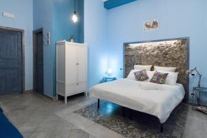 Al Palazzetto di Milo في ميلو: غرفة نوم بجدران زرقاء وسرير ابيض