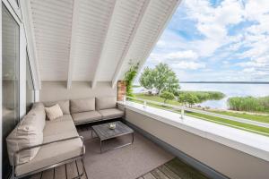 balcone con divano e vista sull'acqua di Wellness-Apartment mit Wasserblick, Pool, Sauna & Fitnessbereich a Rankwitz