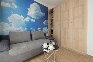 a living room with a couch and clouds mural at Klimaty Bałtyku Studio with Terrace & Parking in Dziwnów by Renters in Dziwnów