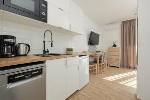 a kitchen with white appliances and a dining room at Klimaty Bałtyku Studio with Terrace & Parking in Dziwnów by Renters in Dziwnów