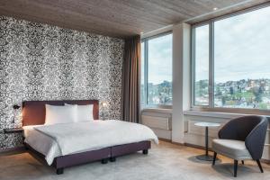um quarto com uma cama, uma cadeira e janelas em b-smart hotel Menziken em Menziken