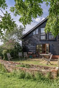 una casa de campo con mesa de picnic y sillas frente a ella en Cart Lodge - Holly Tree Barns, en Halesworth