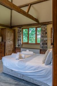 1 cama blanca grande en una habitación con ventanas en Cart Lodge - Holly Tree Barns, en Halesworth