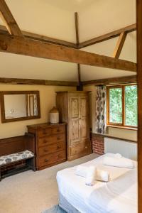 a bedroom with a bed and a dresser in a room at Cart Lodge - Holly Tree Barns in Halesworth