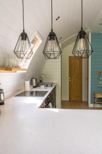 a kitchen with three pendant lights and a sink at Glamping Pod Two - Holly Tree Barns in Halesworth