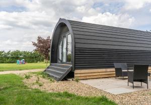 a small black house with a table and chairs at Glamping Pod Two - Holly Tree Barns in Halesworth