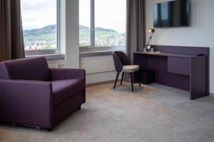 uma sala de estar com uma cadeira, uma secretária e uma televisão em b-smart hotel Menziken em Menziken
