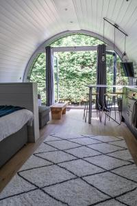 a bedroom with a bed and a table in front of a window at Glamping Pod Two - Holly Tree Barns in Halesworth