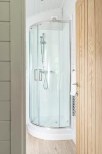a shower in a bathroom with a glass door at Glamping Pod Two - Holly Tree Barns in Halesworth