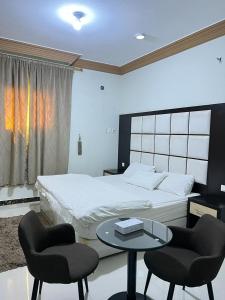 a bedroom with a bed and two chairs and a table at الراحة بلازا للشقق المفروشة in Sharurah