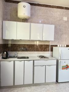 uma cozinha com armários brancos e um frigorífico branco em الراحة بلازا للشقق المفروشة em Sharurah