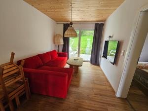 a living room with a red couch and a chair at Rustikale Ferienwohnung auf Rups Hof in Oberhöcking