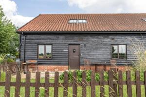 a house with a wooden fence in front of it at The Dairy - Holly Tree Barns in Halesworth