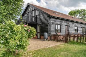 a small wooden house with a fence in front of it at The Dairy - Holly Tree Barns in Halesworth