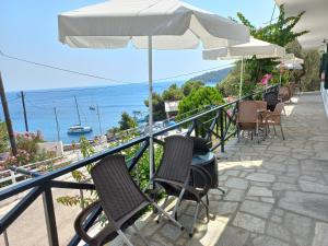 a balcony with chairs and an umbrella and the ocean at Stafylos Rooms in Stafylos