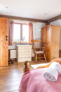 a bedroom with a bed and a chair at The Dairy - Holly Tree Barns in Halesworth