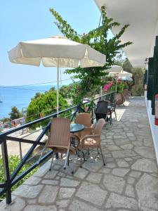 a patio with chairs and tables and an umbrella at Stafylos Rooms in Stafylos
