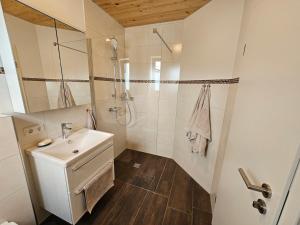 a white bathroom with a sink and a shower at Rustikale Ferienwohnung auf Rups Hof in Oberhöcking