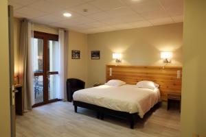 una camera da letto con un letto grande con testiera in legno di Hôtel Belleville a Lamalou-les-Bains
