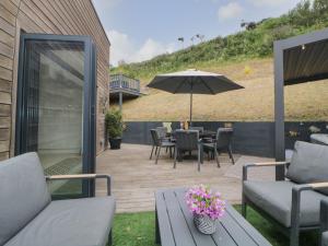 eine Terrasse mit einem Tisch, Stühlen und einem Sonnenschirm in der Unterkunft 12 Beachdown in Kingsbridge