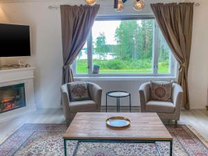 a living room with two chairs and a table and a fireplace at Holiday Home Rovaniemi ainola by Interhome in Oikarainen