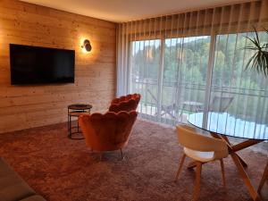 een woonkamer met een televisie en een tafel en stoelen bij Hôtel Restaurant La Couronne by K in Reipertswiller