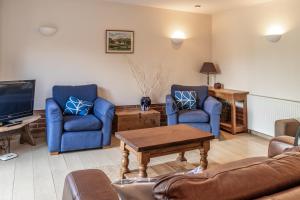 a living room with a couch and two chairs and a tv at The Stables - Holly Tree Barns in Halesworth