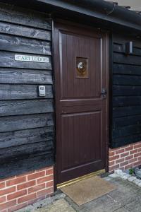 une porte brune avec un chien sur un bâtiment dans l'établissement Cart Lodge - Holly Tree Barns, à Halesworth