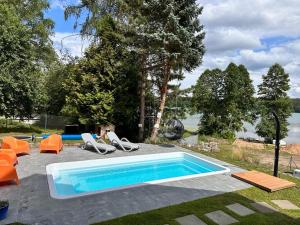 a swimming pool with orange chairs and a swimming pool at HonoLulu Dom Wakacyjny z balią, sauną i basenem in Kłaczno