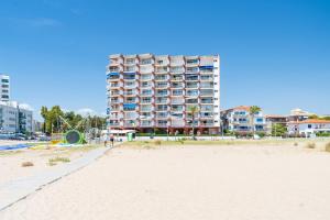 a tall building on the beach with a sandy beach at Edificio Victoria 5º-7ª in La Playa