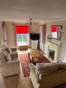 a living room with two couches and a fireplace at Wendy Lodge- Chalet Cottage in Padstow