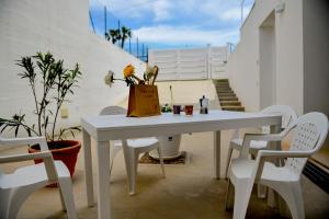 una mesa blanca y sillas con una maceta de flores. en Apartment Laura, en Avola