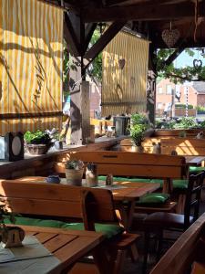 een restaurant met houten tafels, stoelen en planten bij Gaststätte und Pension Zur Schiene in Merseburg